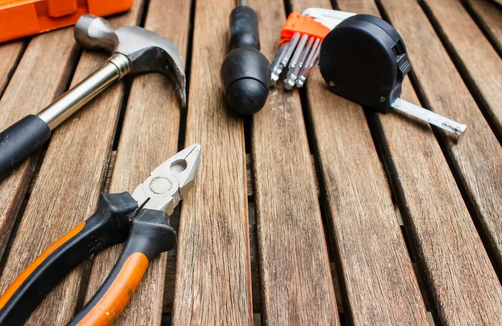 Hammer, pliers, screwdriver, hex keys and tape measure on wooden slats
